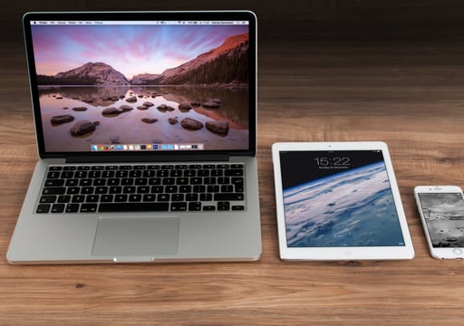 A laptop, a tablet and a mobile phone on a table. 