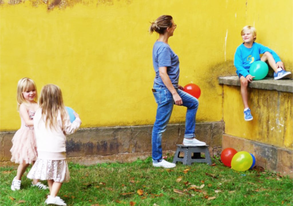 A woman playing with children in a backyard 
