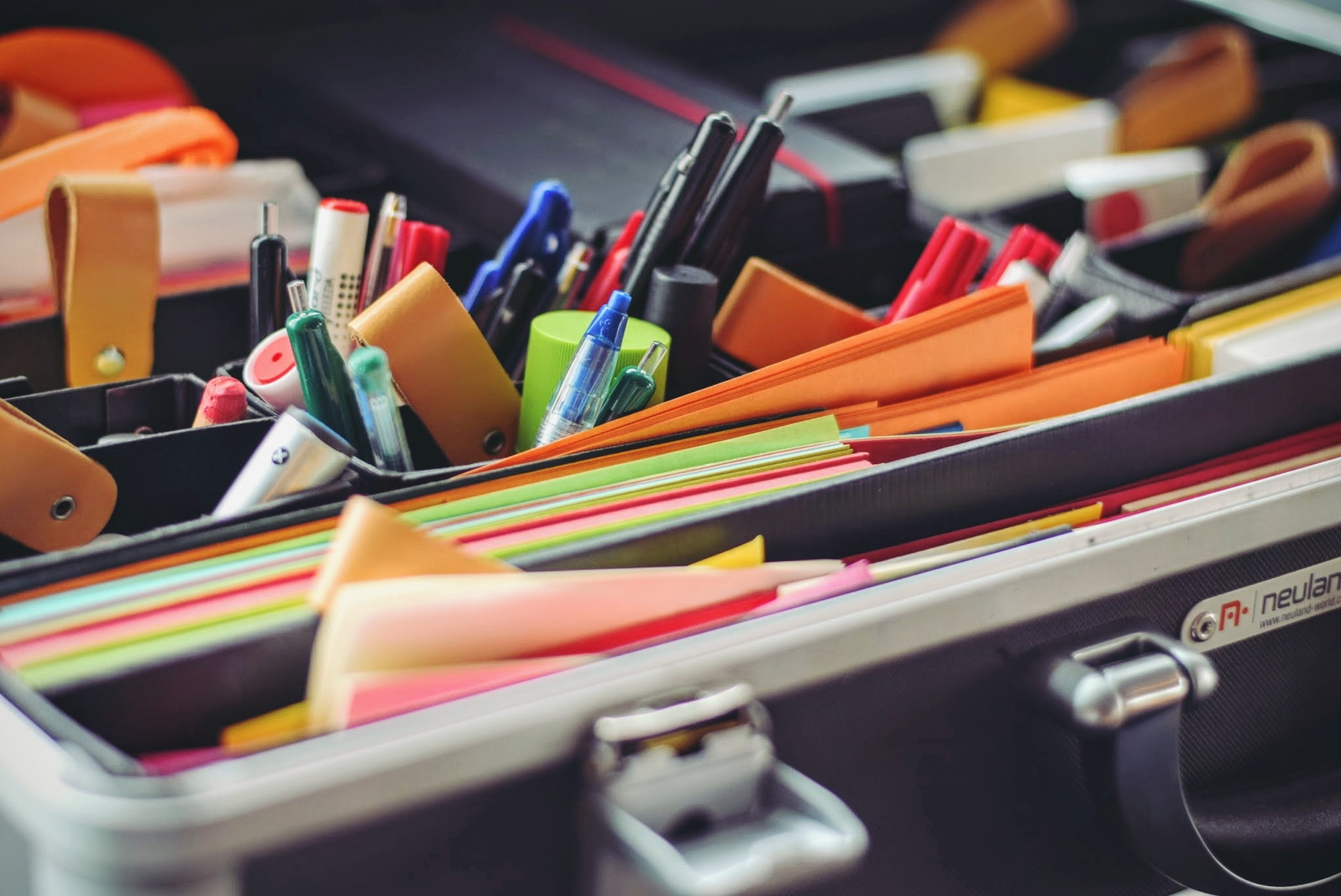 Various writing tools like pens, pencils, coloured paper, etc in a box 